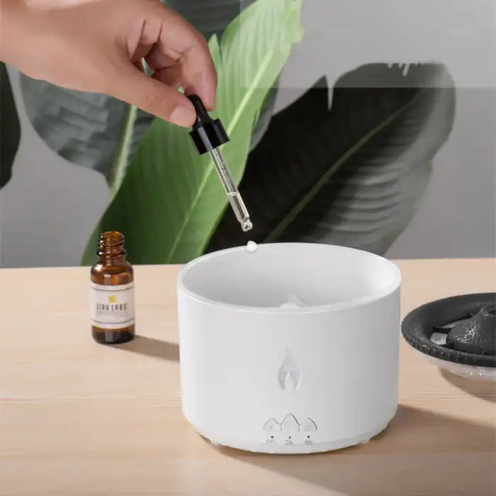 .Humidifier being refilled with essential oil using dropper on light wooden table