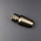 Aluminum pill case with bronze finish laying flat on a dark surface showcasing its compact cylindrical design.