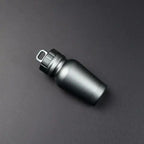 Gunmetal black aluminum pill case with looped lid placed on black background for sleek industrial look.