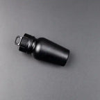 Matte black aluminum pill case on dark backdrop with smooth finish and sturdy looped cap.