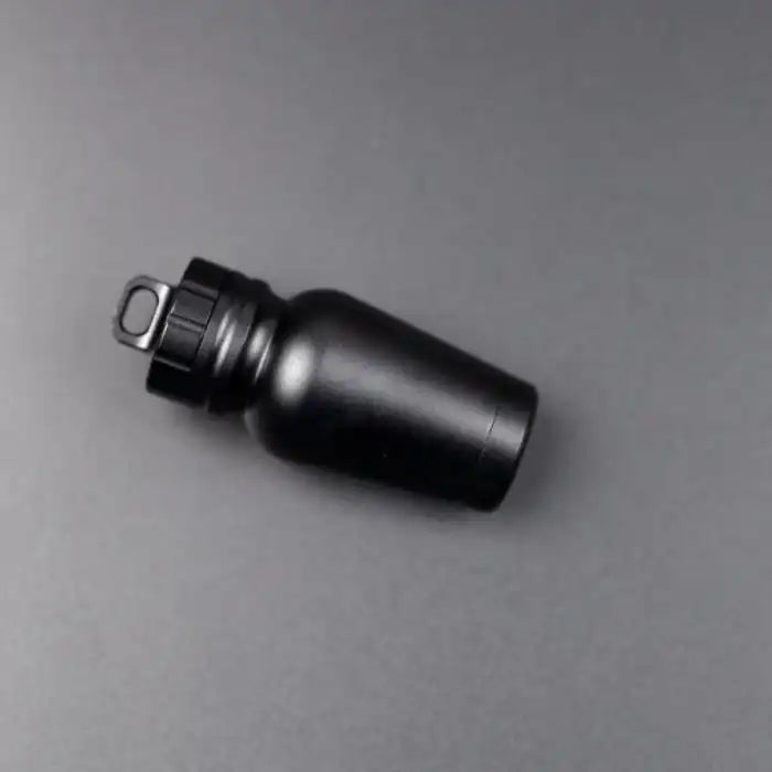 Matte black aluminum pill case on dark backdrop with smooth finish and sturdy looped cap.