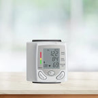 Front view of wrist blood pressure tester with digital screen showing systolic, diastolic, and pulse.