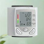 Blood pressure tester with large LCD screen and color-coded indicators against a green background.