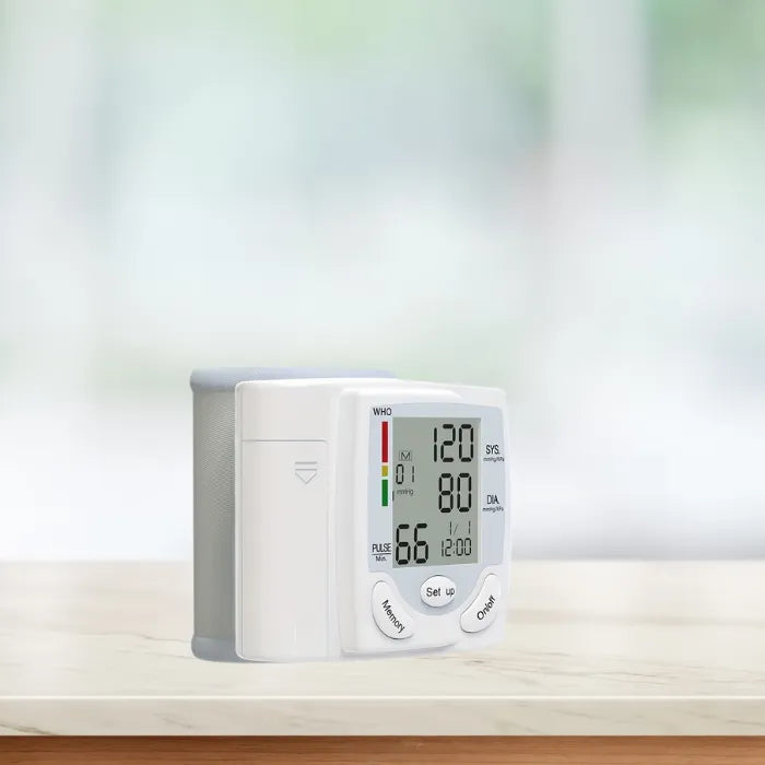 Compact wrist blood pressure tester placed on a white marble counter with blurred background.