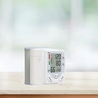 Compact wrist blood pressure tester placed on a white marble counter with blurred background.