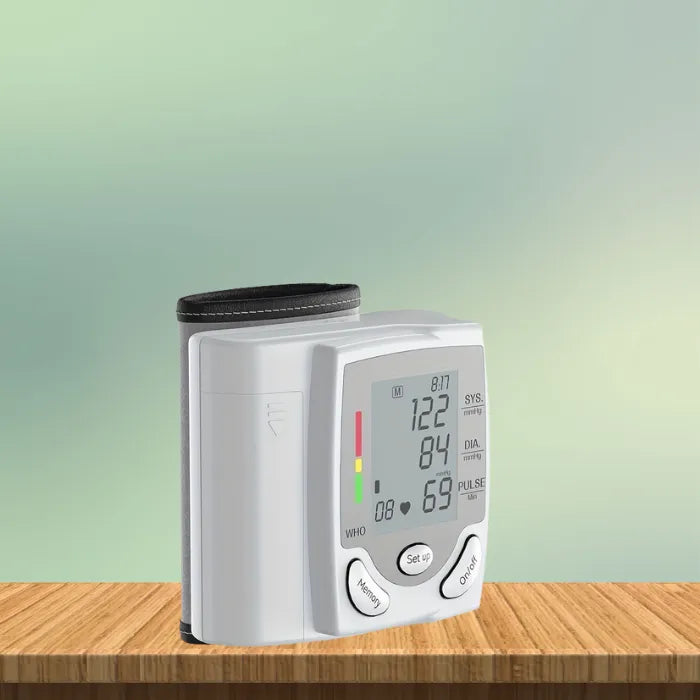 Wrist blood pressure tester standing upright on wooden surface with green gradient background.