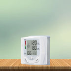 Blood pressure tester with clear screen and soft green background placed on wooden desk surface.