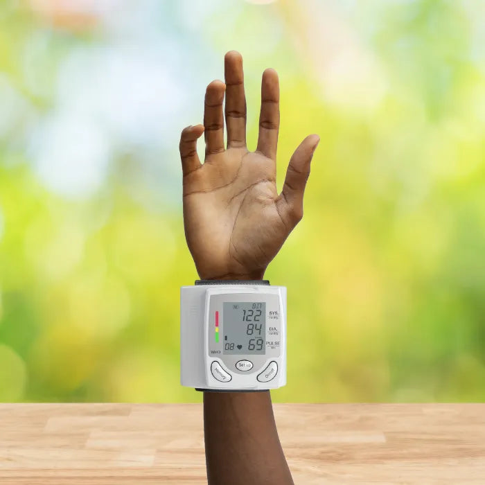 Blood pressure tester worn on raised wrist against bright blurred background showing accurate readings.