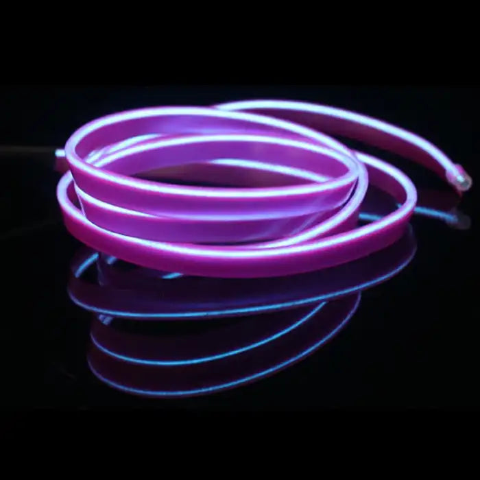 Purple car interior LED light strip coiled with glowing edge on a glossy black surface