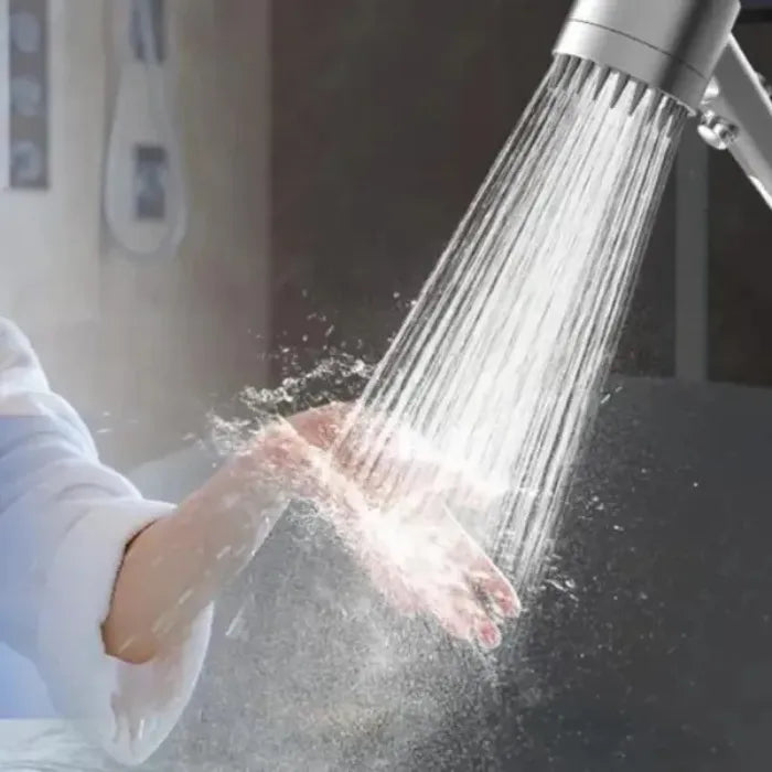 High pressure shower head spraying strong water stream onto a hand in close-up.