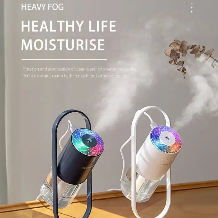 Humidifier with rainbow LED light releasing heavy mist in modern black and white finish.