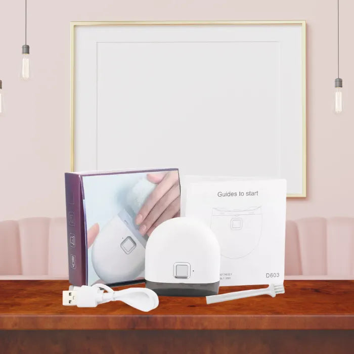 Infant nail clipper kit with box, USB cable, manual, and tool displayed on table.