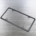Single black license plate holder frame angled on brushed steel surface.