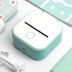 Mini Thermal Printer placed on white desk next to notebooks and accessories