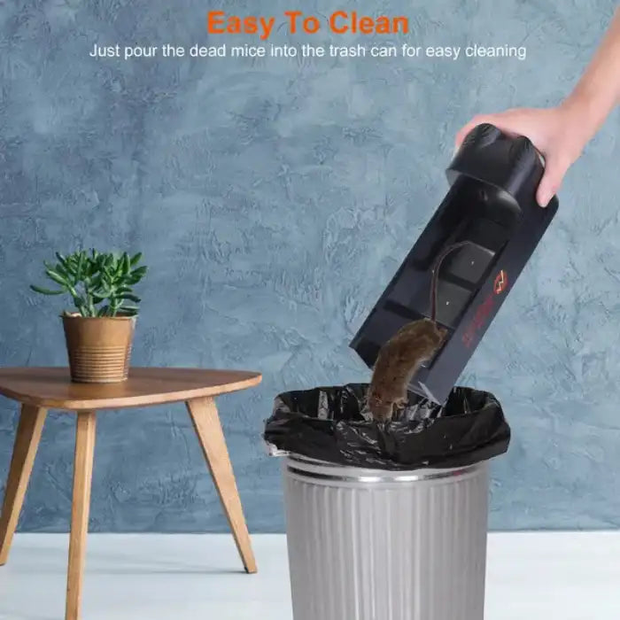 Mouse trap being emptied into trash can, demonstrating simple and hygienic dead rodent disposal design.