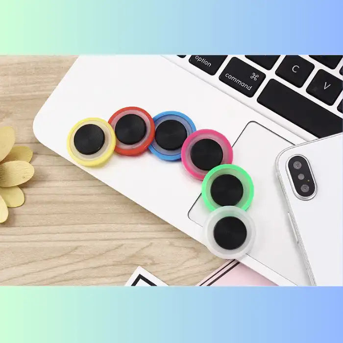 Phone Joystick color variants placed beside a laptop and smartphone for accessory showcase