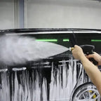 Pressure washer spraying thick foam on black vehicle during car wash using white tip nozzle