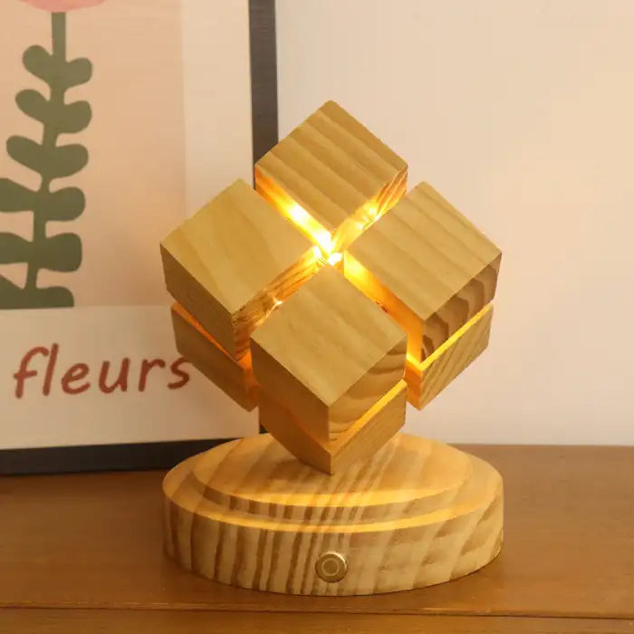 Rubix cube night light battery power glowing warmly on wooden table beside wall art