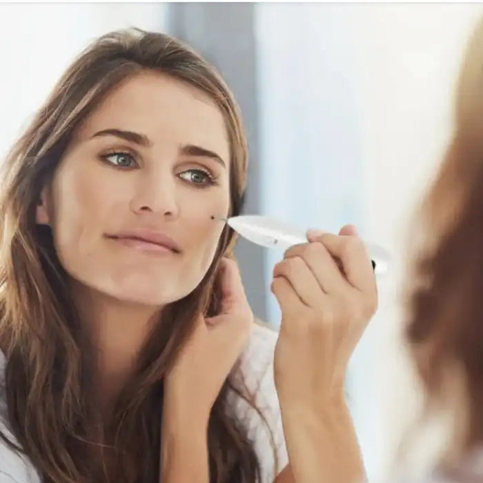 Skin Tag Remover pen being used by a woman to target a dark spot on her cheek.