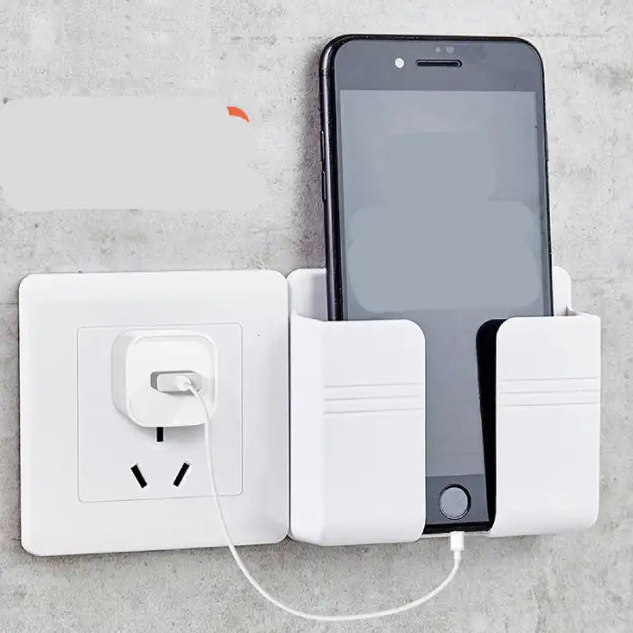 Wall mount phone holder securely holding black phone while charging at a wall power outlet.