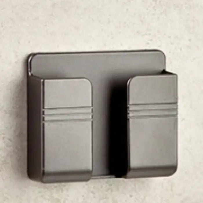 Metallic black wall mount phone holder mounted on textured surface with minimalist dual-clip design.