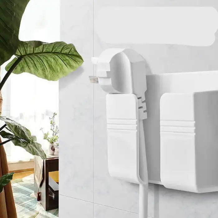 Side view of wall mount phone holder in use holding cable neatly on tiled wall next to green plant.